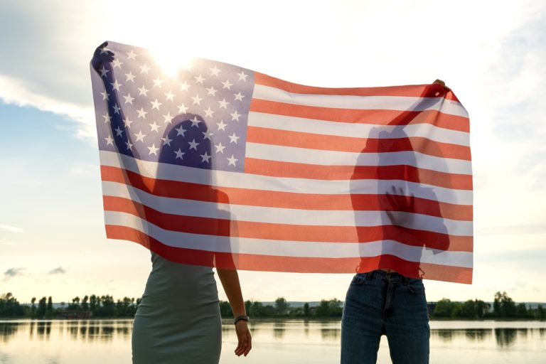 two people holding a flag in front of the sun. place immigration ads